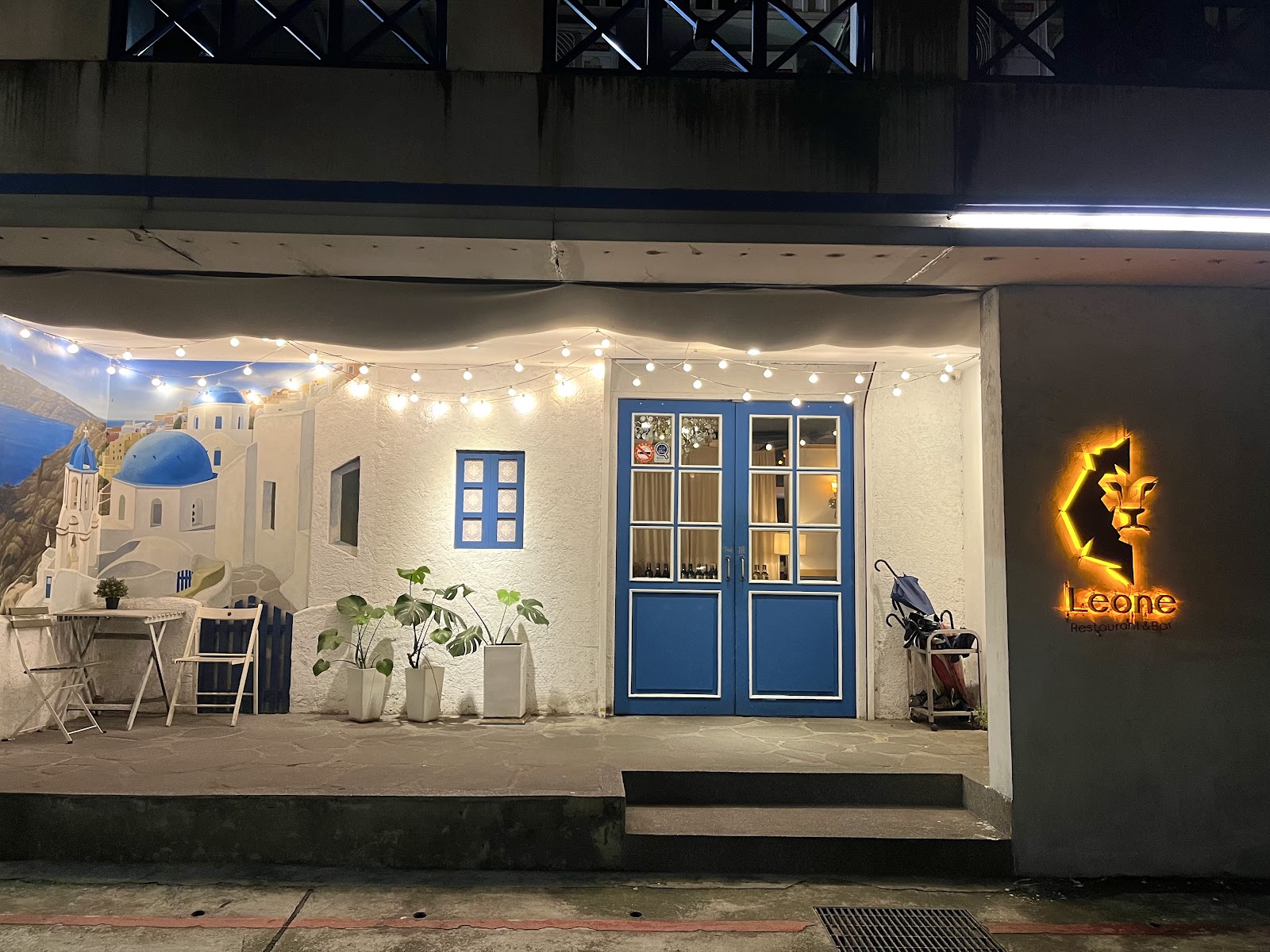 Leone 夜晚店門口，聖托里尼藍頂壁畫與發光獅子招牌